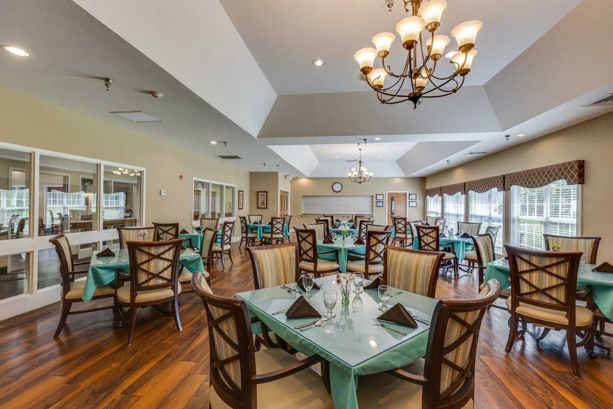 A well-appointed dining room with neatly arranged tables and chairs under a stylish chandelier.