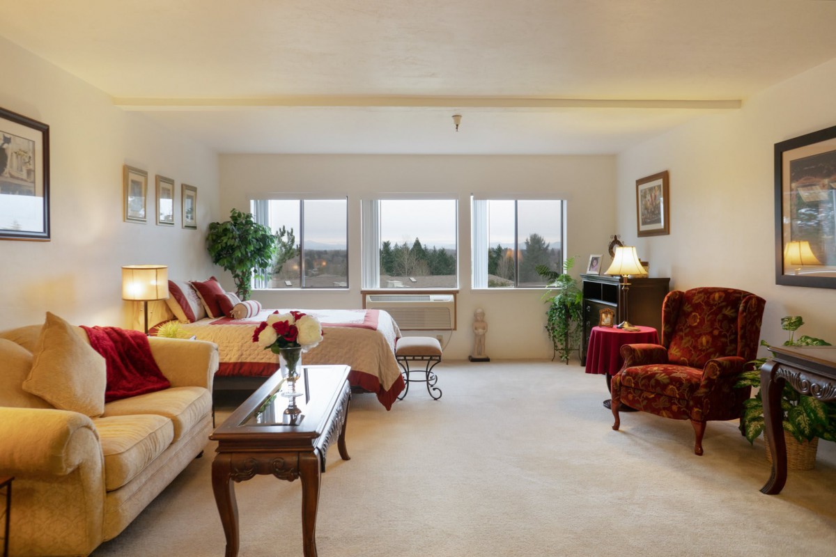 A cozy and spacious bedroom with large windows, elegant furniture, and warm decor.