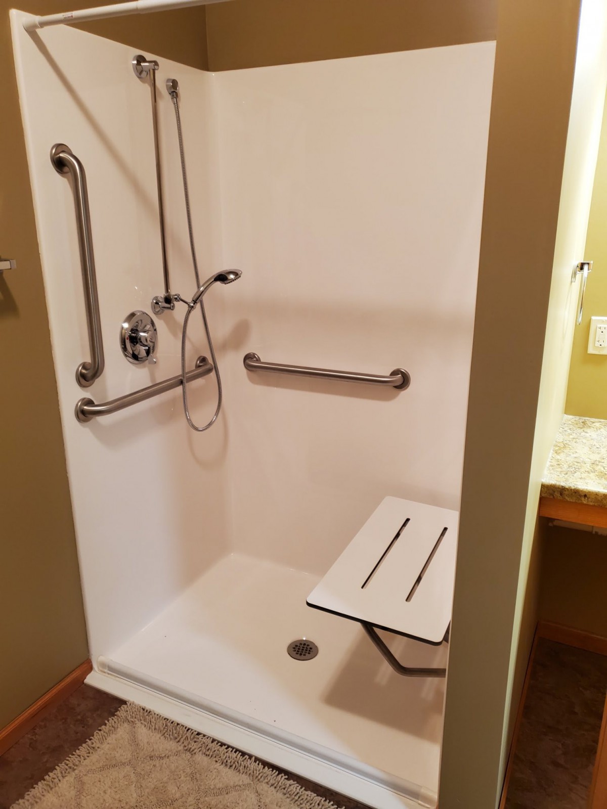 An accessible shower equipped with a foldable seat and grab bars.
