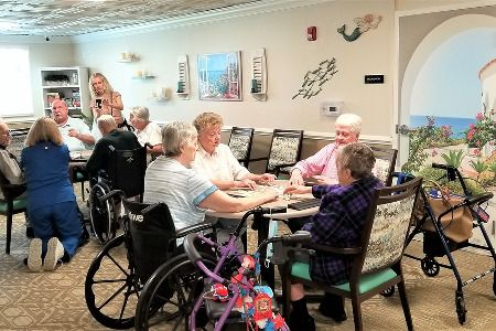 A group of elderly individuals gathered around a table in a nursing home, engaging in a social activity.