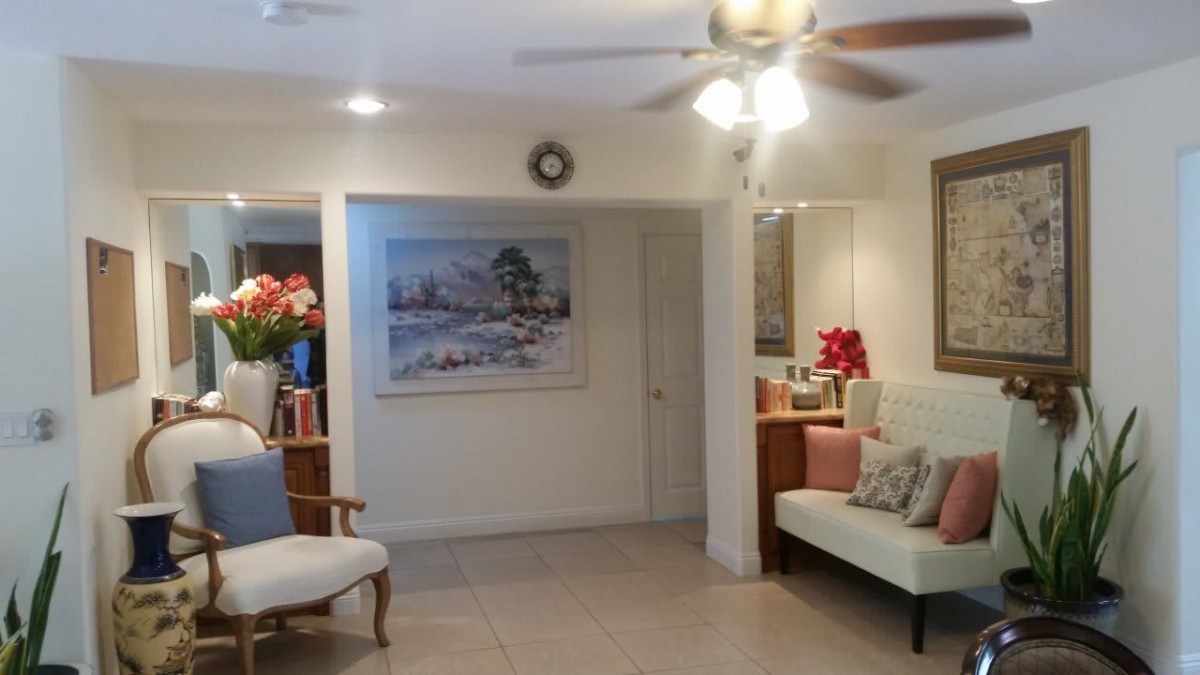 A cozy living room with a sofa, painting, and ceiling fan.