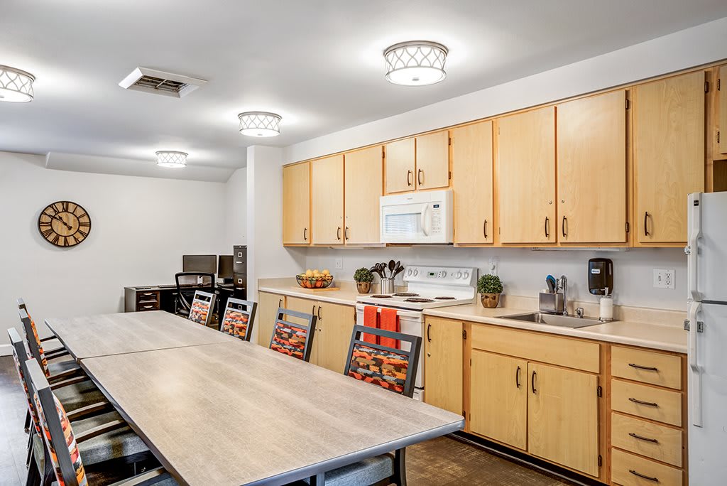 A modern kitchen with wooden cabinets and a large dining table surrounded by chairs.