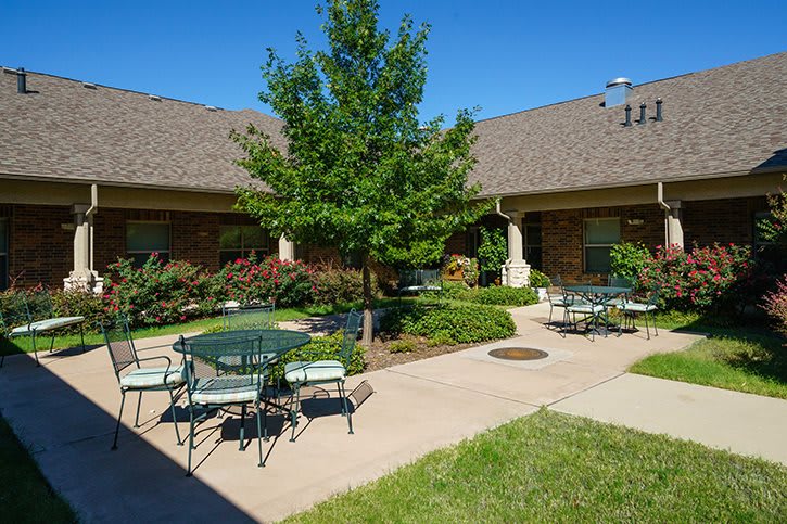 A sunny courtyard with outdoor seating and lush greenery.
