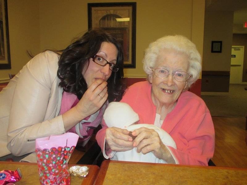 An older woman and a younger woman sharing a joyful moment together indoors.
