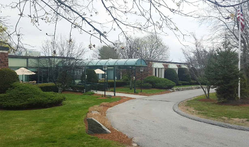 A serene pathway leading to a building surrounded by trees on a foggy day.