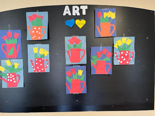 A vibrant display of children's art featuring colorful flower vases on a bulletin board.
