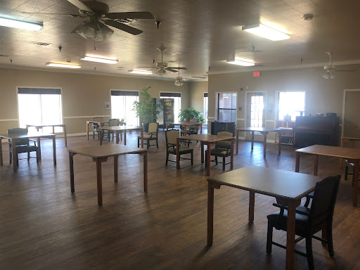A spacious common area featuring neatly arranged tables and chairs, illuminated by natural light.