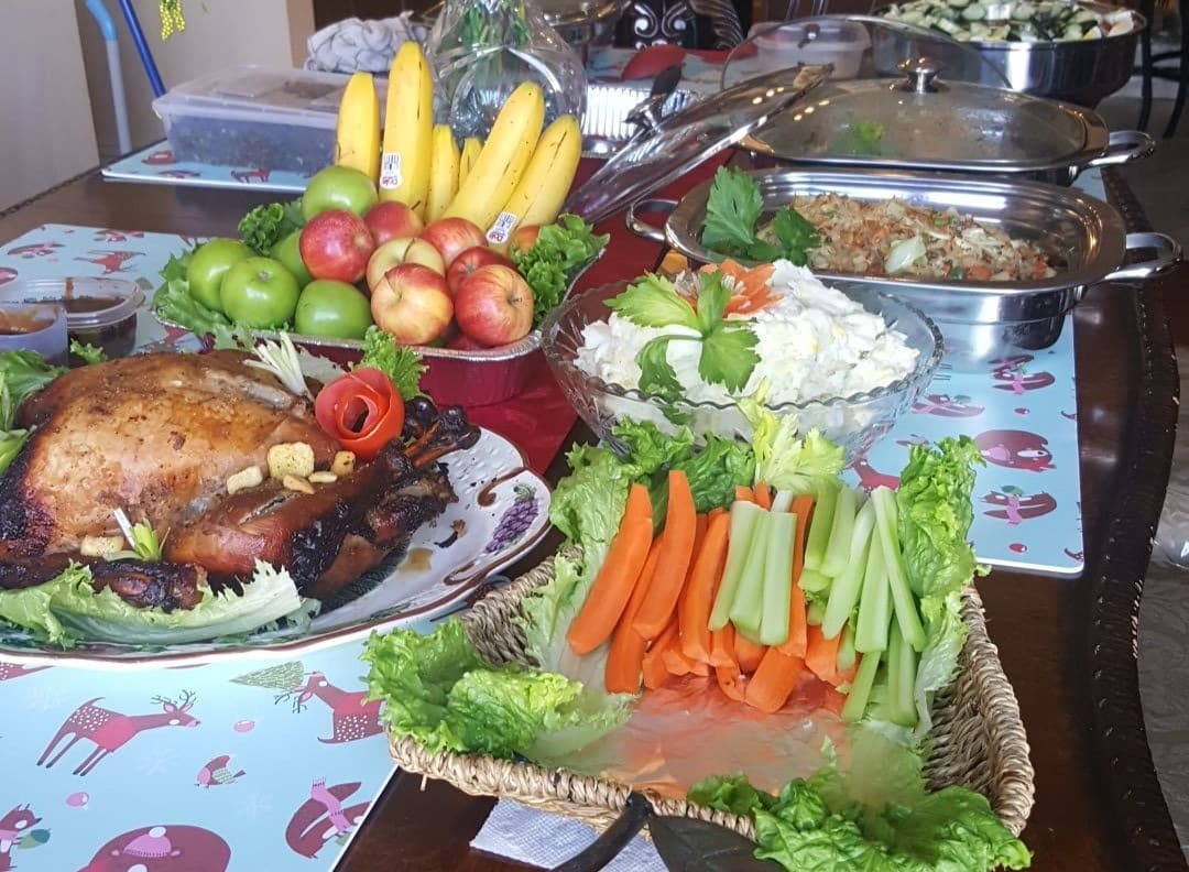 A buffet spread featuring fruits, vegetables, and roast meat.