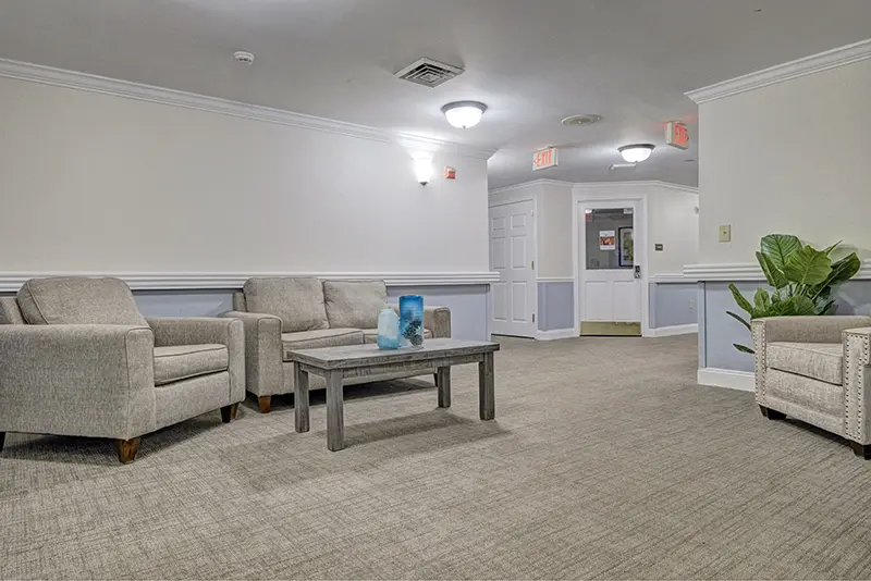 A cozy waiting area with comfortable chairs and a table, warmly lit by overhead lighting.