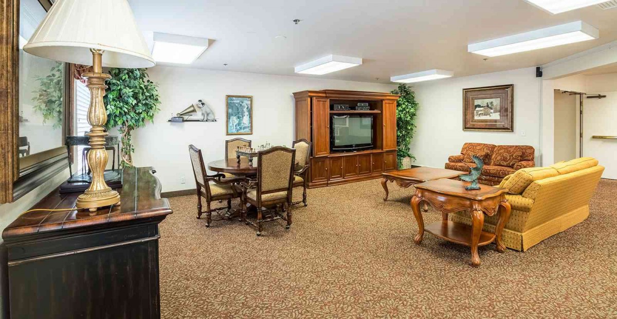 A cozy living room featuring a seating area, television, and elegant wooden furniture.