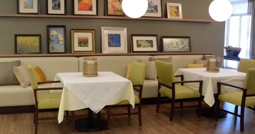 A cozy restaurant dining area with neatly arranged tables and chairs, adorned with various framed artworks on the walls.