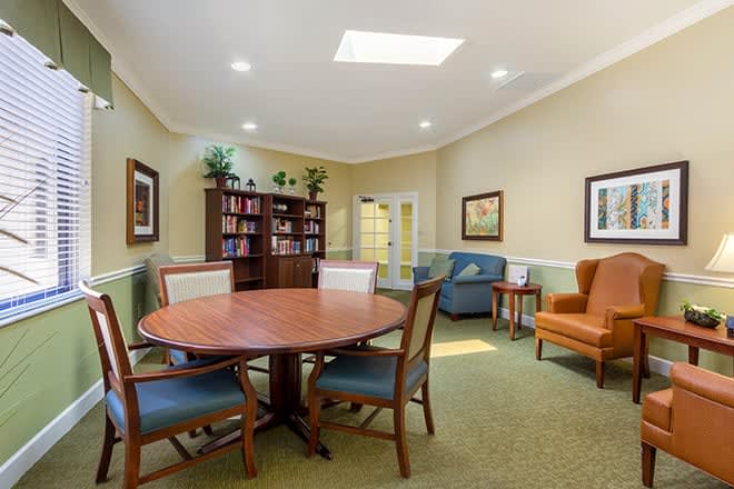 A cozy living room with a round table, chairs, bookshelves, and comfortable seating.
