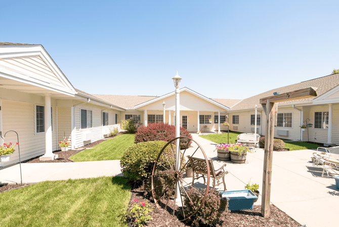 A sunny courtyard with well-maintained gardens and seating areas surrounded by a building.
