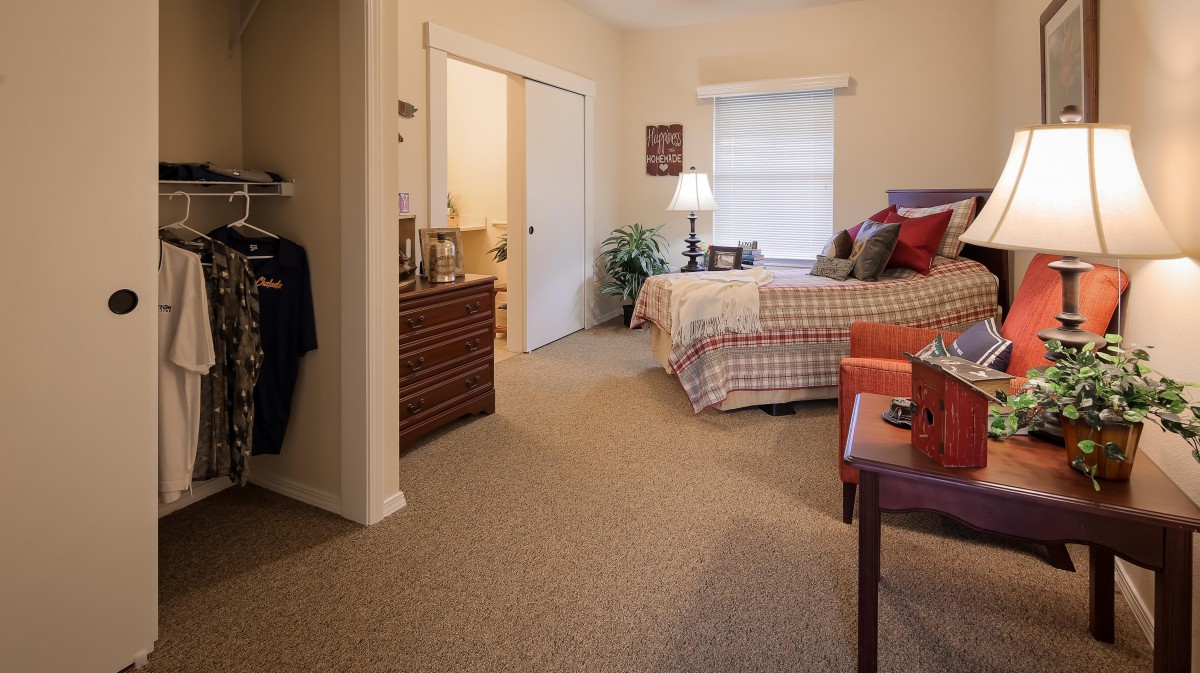 A cozy bedroom with a neatly arranged bed, dresser, and warm lighting.