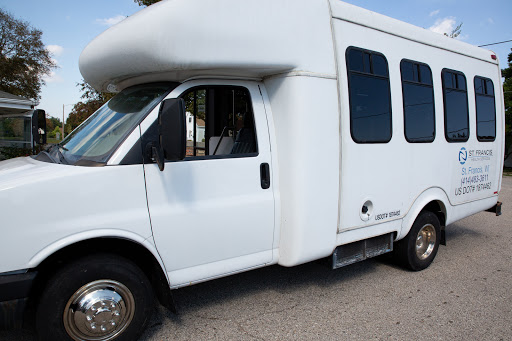 A side view of a white shuttle van parked on the street.