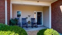A cozy porch with two rocking chairs and potted plants beside the entrance.