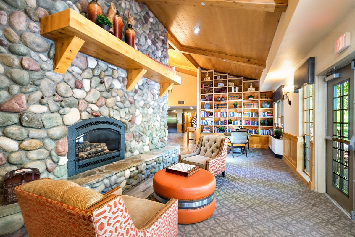 A cozy lounge with a stone fireplace and comfortable seating, enhanced by a library wall.