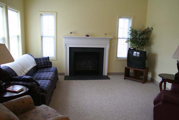 A cozy living room featuring a fireplace, sofa, and a TV in the corner.