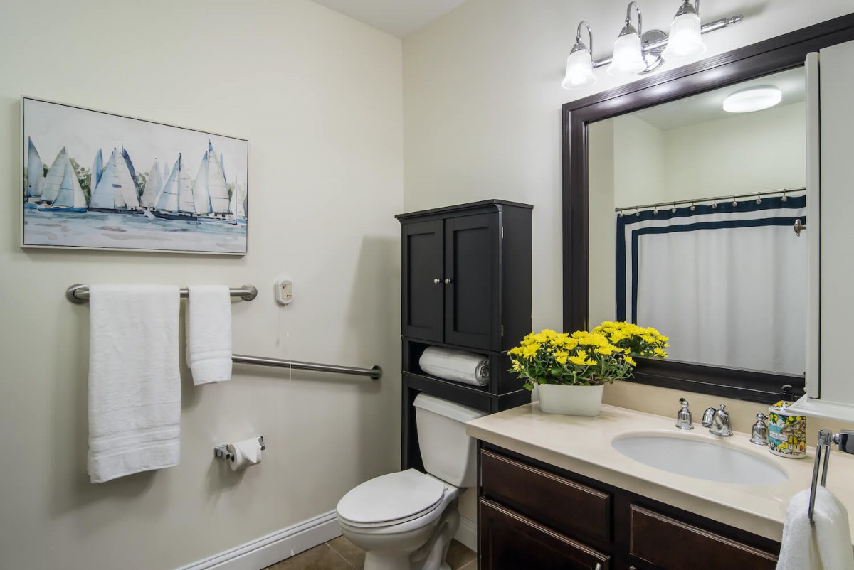 A clean and modern bathroom with a toilet, sink, and cabinet, adorned with flowers and nautical decor.