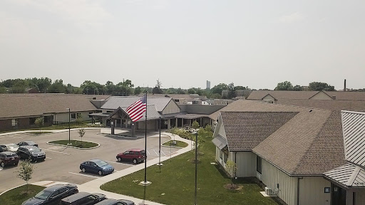 A view of a suburban residential area featuring an American flag and several buildings under a clear sky.