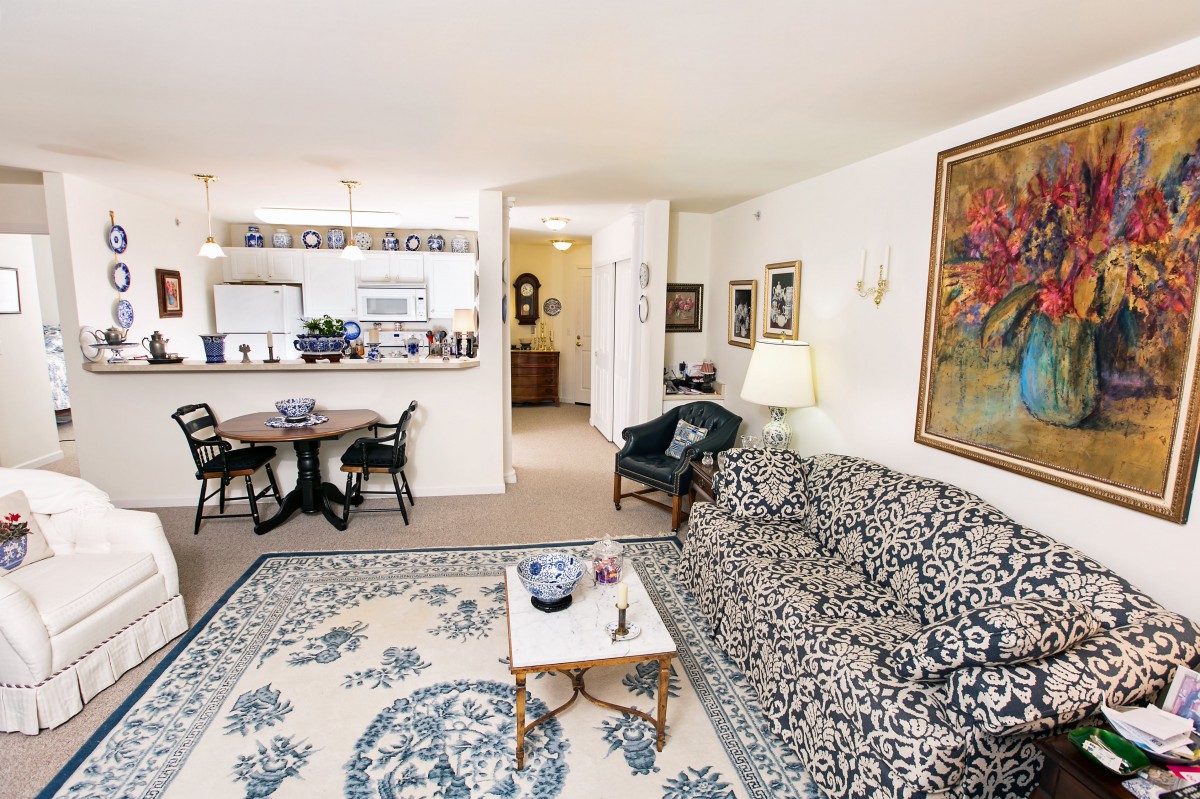 A cozy living room with a patterned sofa, decorative rug, and dining area visible in the background.