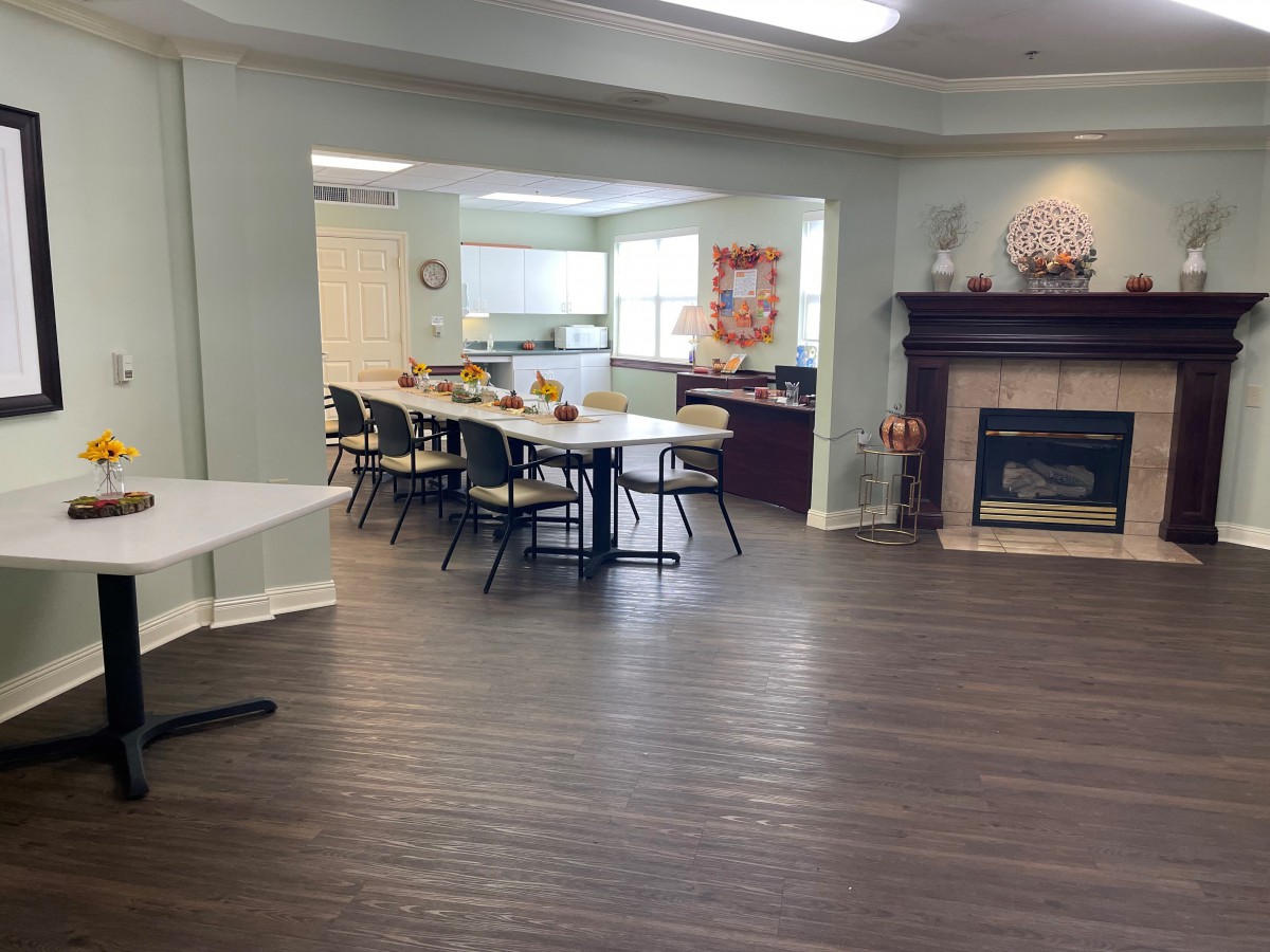 A spacious dining and meeting area with a cozy fireplace, featuring several tables and chairs arranged for a communal setting.
