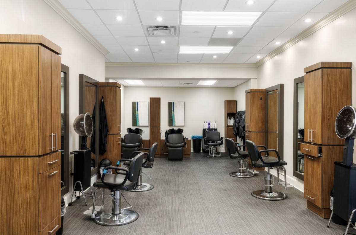A clean and modern hair salon interior with multiple barber chairs and mirrors.