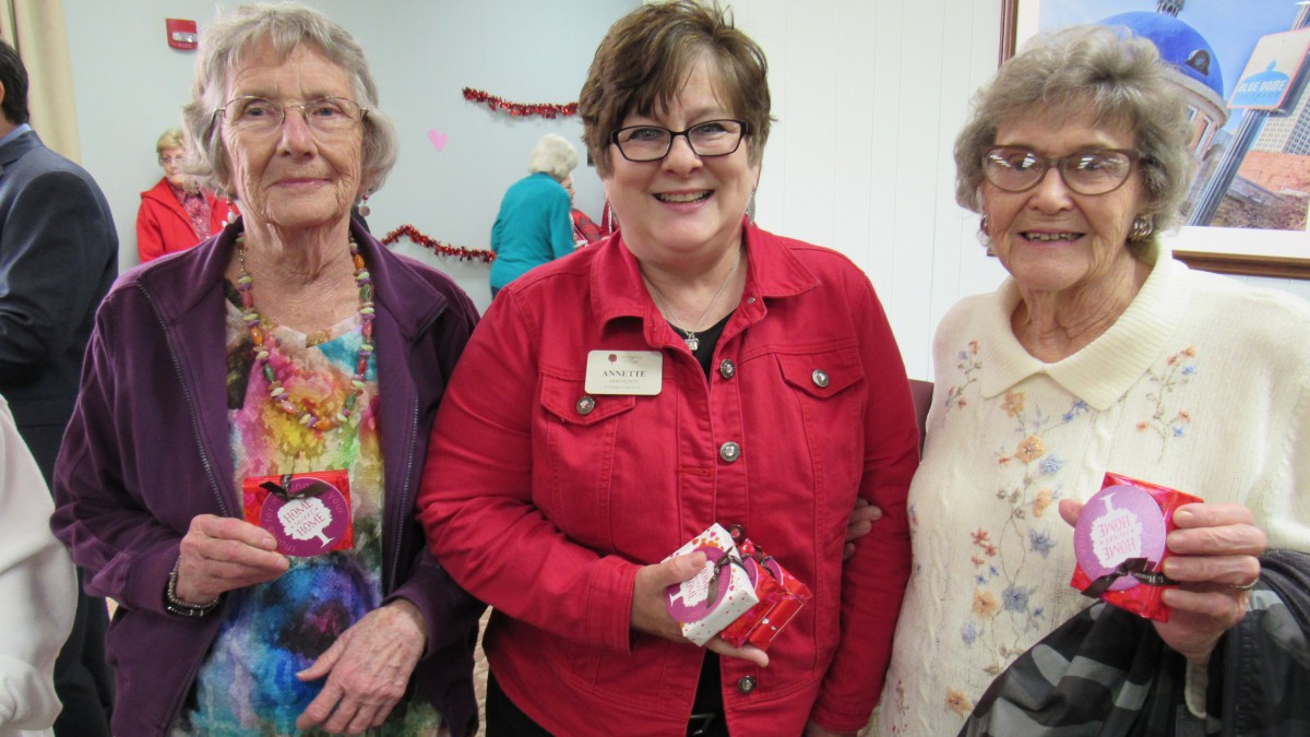 A group of women smiling at an indoor gathering.