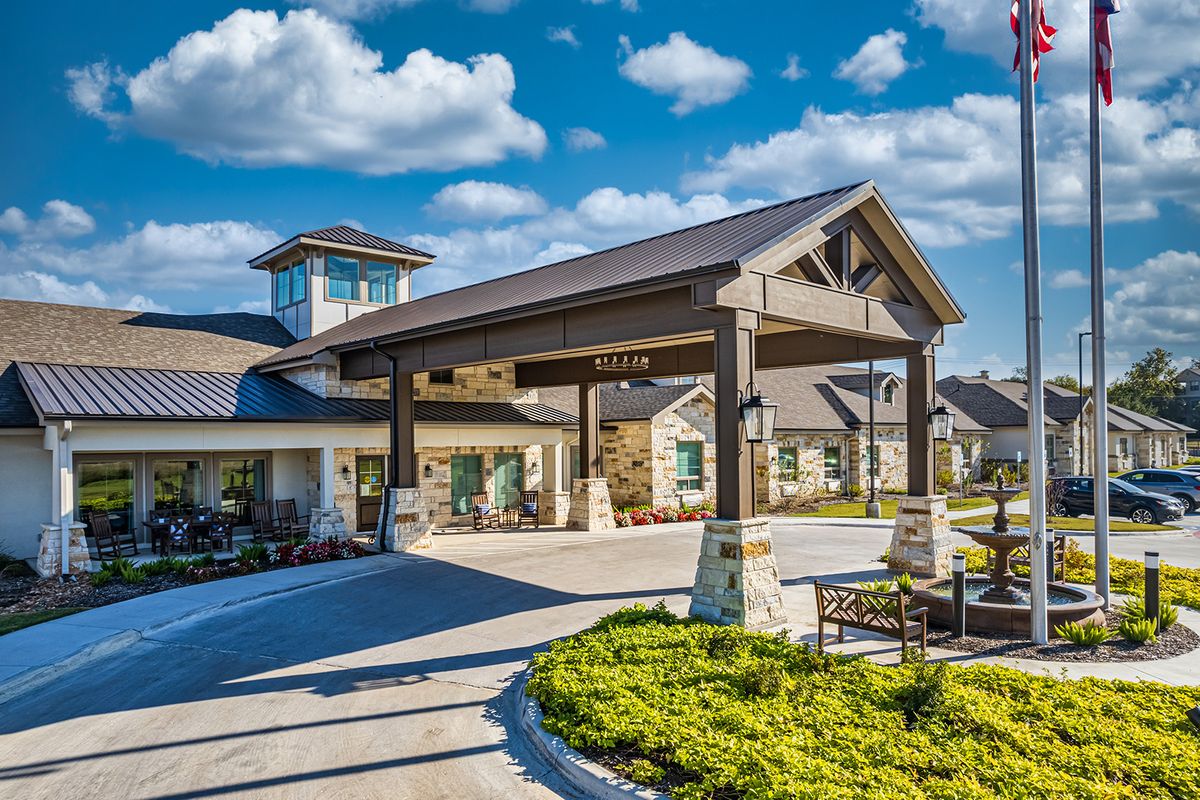 A modern building entrance with landscaped surroundings under a bright sky.