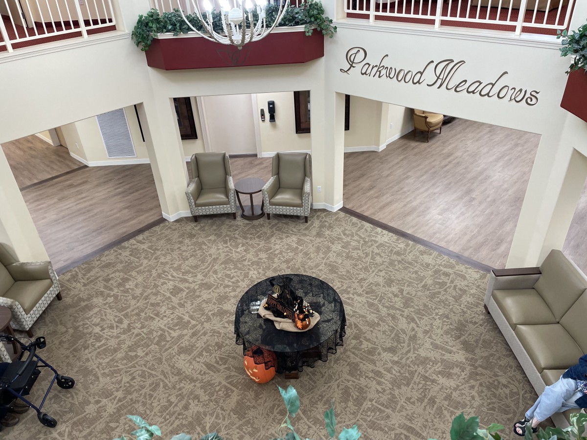 An elegant theater lobby with comfortable seating and a decorative table centerpiece under a chandelier.