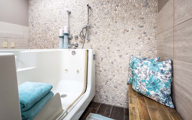 A modern bathroom featuring a sleek bathtub with turquoise towels and stylish tile walls.