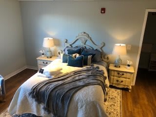 A cozy bedroom with a neatly made bed, accented pillows and blankets, flanked by two nightstands with lamps.