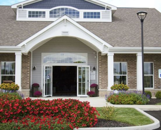 A welcoming building entrance with a well-maintained garden and colorful flowers.