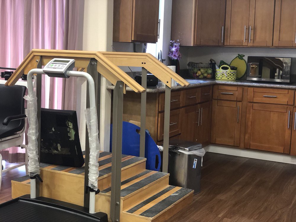 Indoor physical therapy setup with training stairs next to a kitchen area.