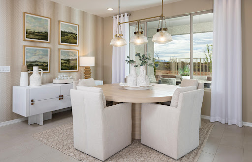 A stylish and modern dining area featuring a round table, plush white chairs, and ample natural light.