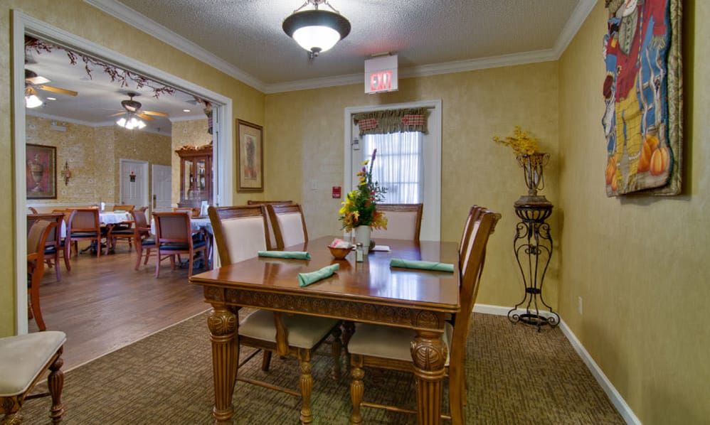 A cozy dining room with a wooden table set for four, featuring elegant decor and soft lighting.