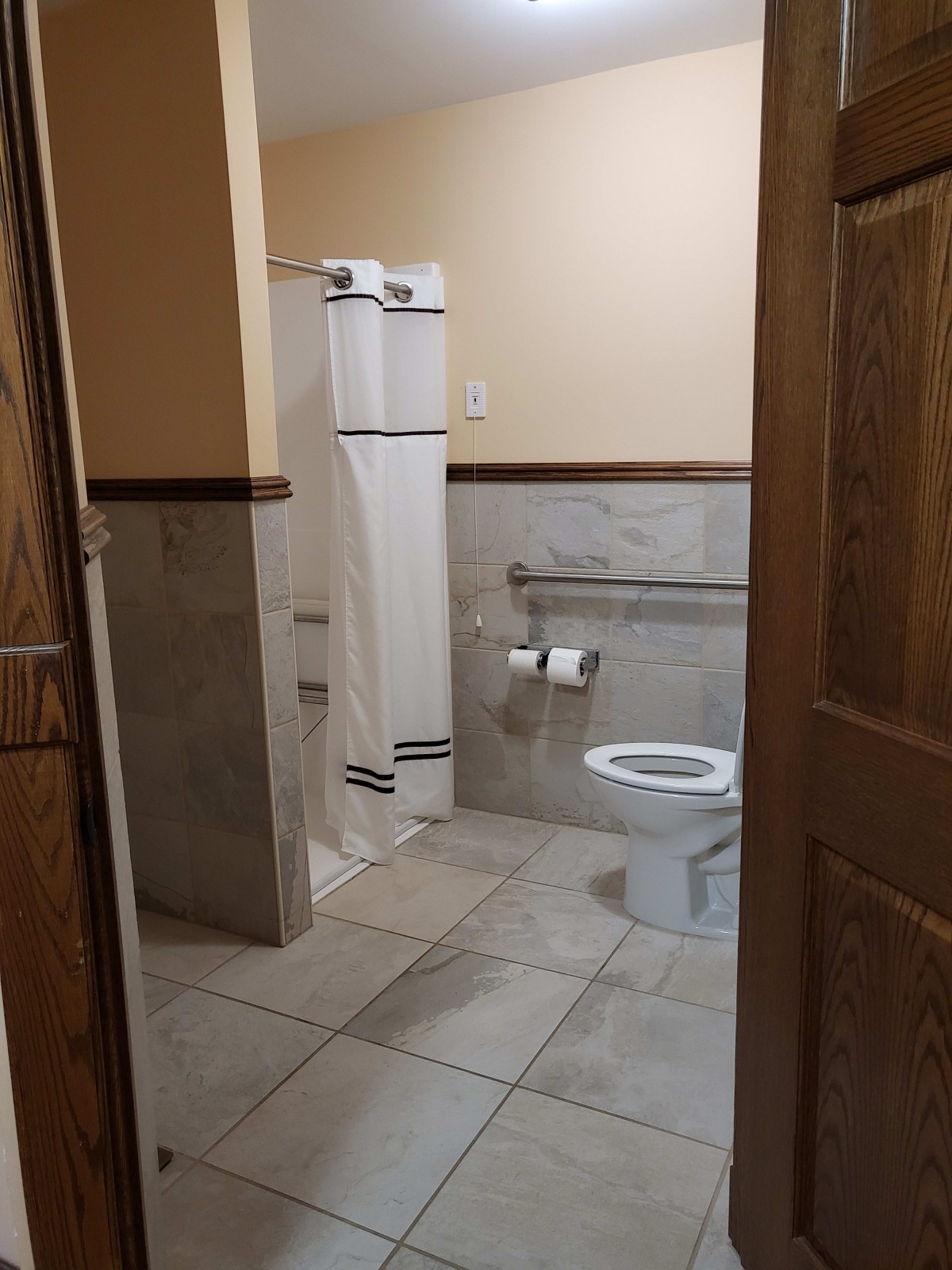 A view of a bathroom featuring a toilet, shower, and tiled flooring.