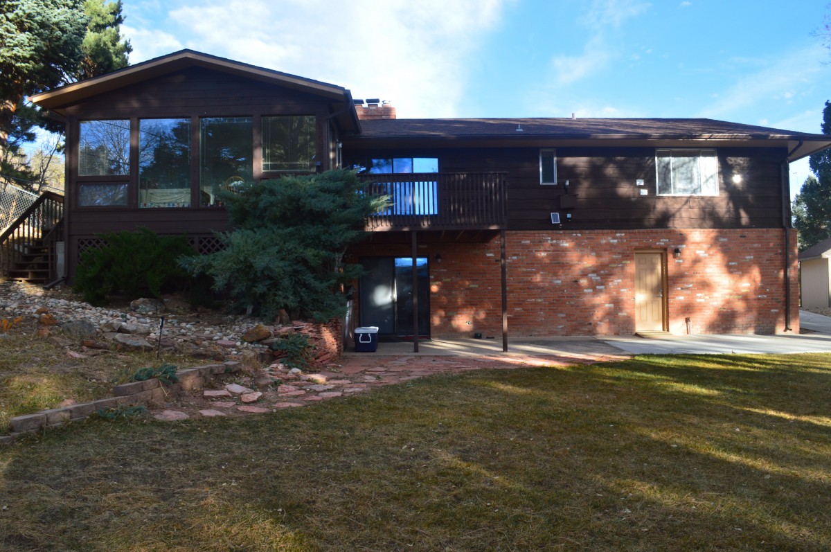 A two-story brick house with a large front lawn and clear skies.
