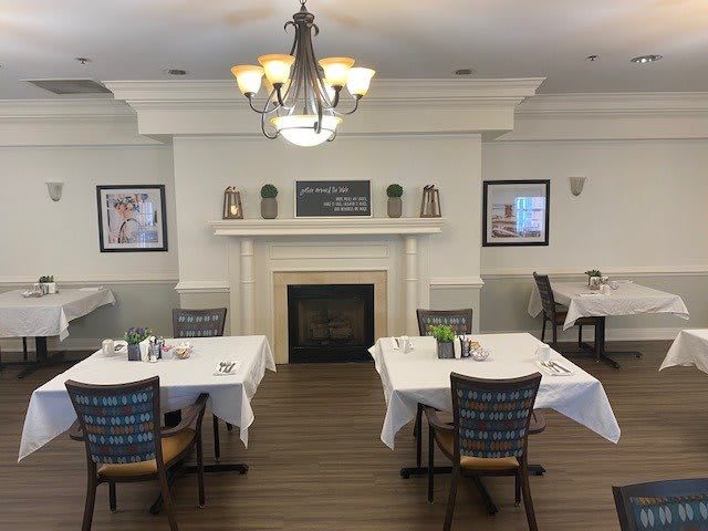 A cozy restaurant dining area with neatly set tables and a central fireplace.