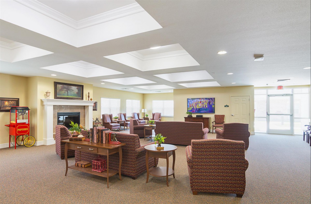 A spacious and well-lit living room with multiple seating areas, featuring sofas, tables, and a fireplace.