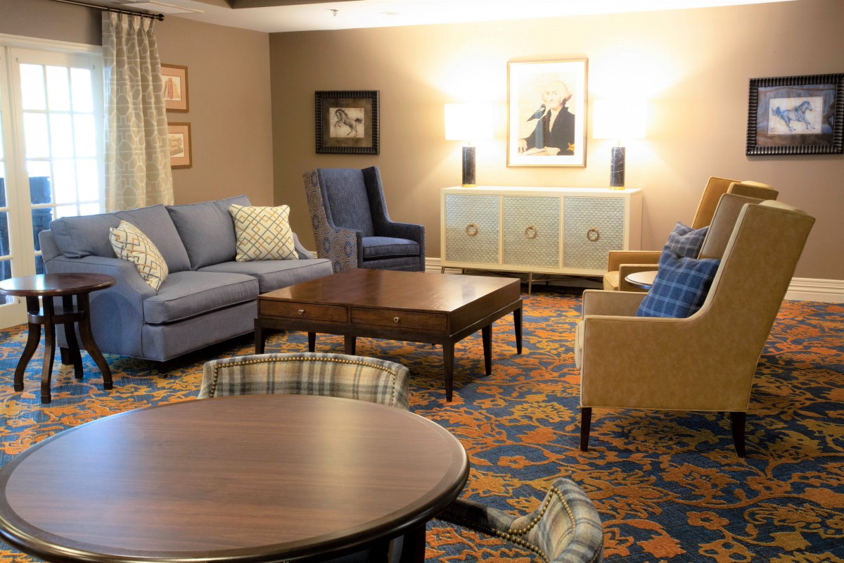 A cozy living room with sofas, chairs, and a coffee table, featuring elegant decor and artwork on the walls.