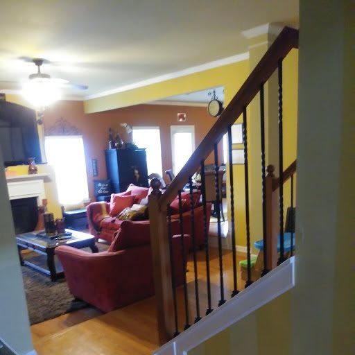 A cozy living room with a staircase view, featuring sofas, a television, and a fireplace.