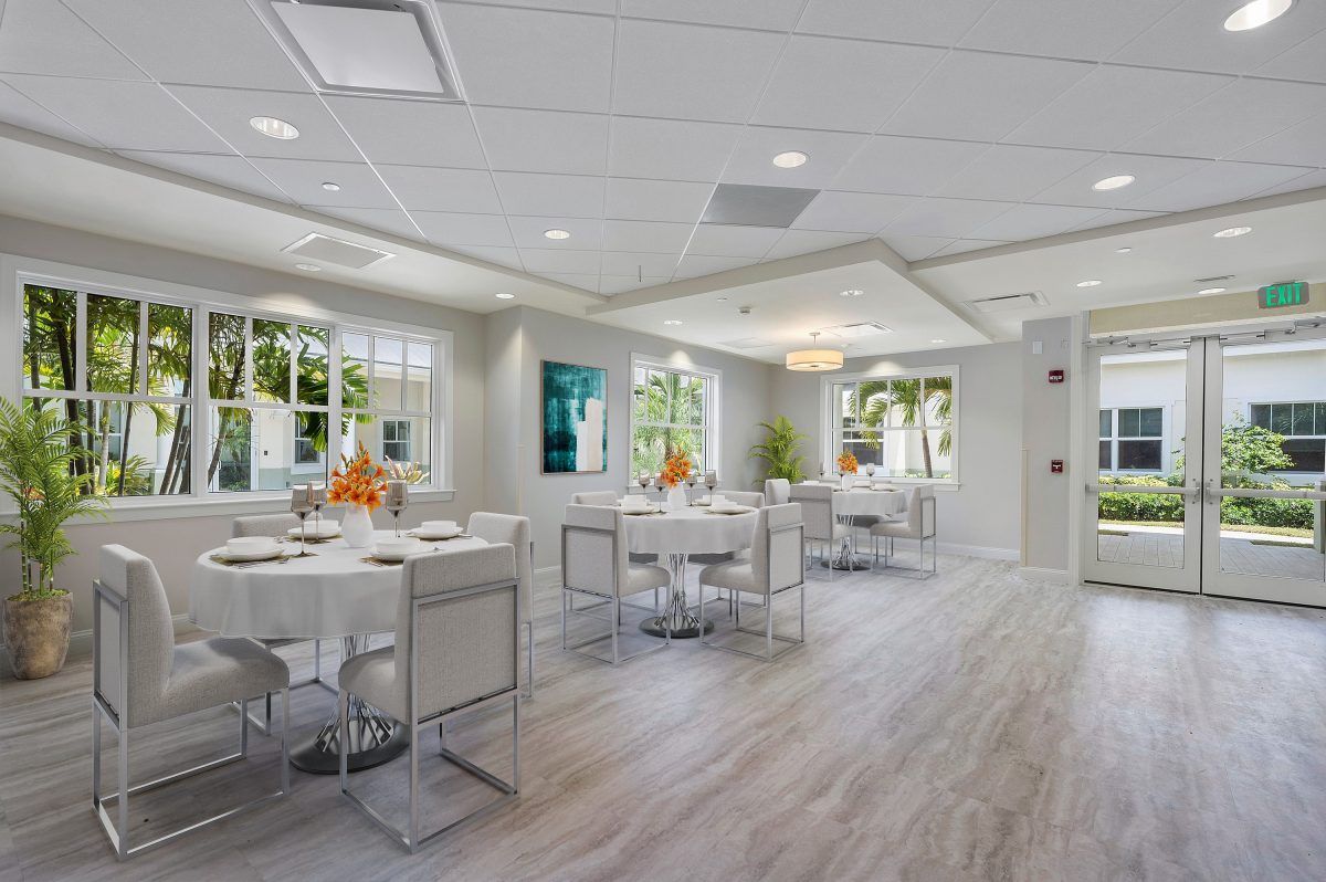 A modern, white-themed dining room featuring minimalist furniture and large windows.