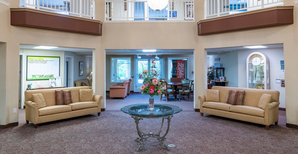 A cozy lobby area with sofas and a glass table featuring a floral arrangement.