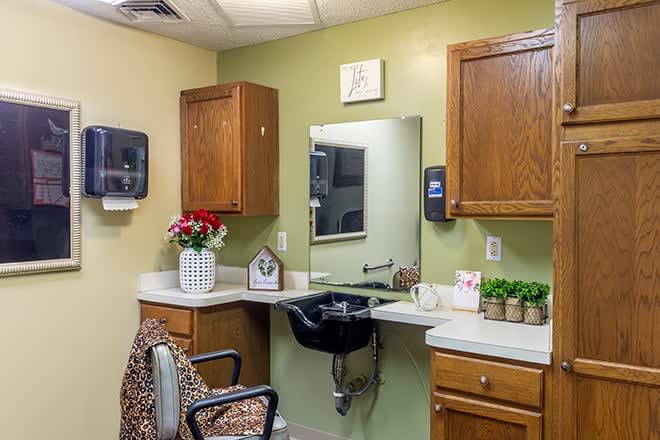 A cozy salon interior with a sink, mirror, and cabinets.