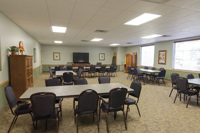 An empty conference room with tables and chairs arranged for a meeting.