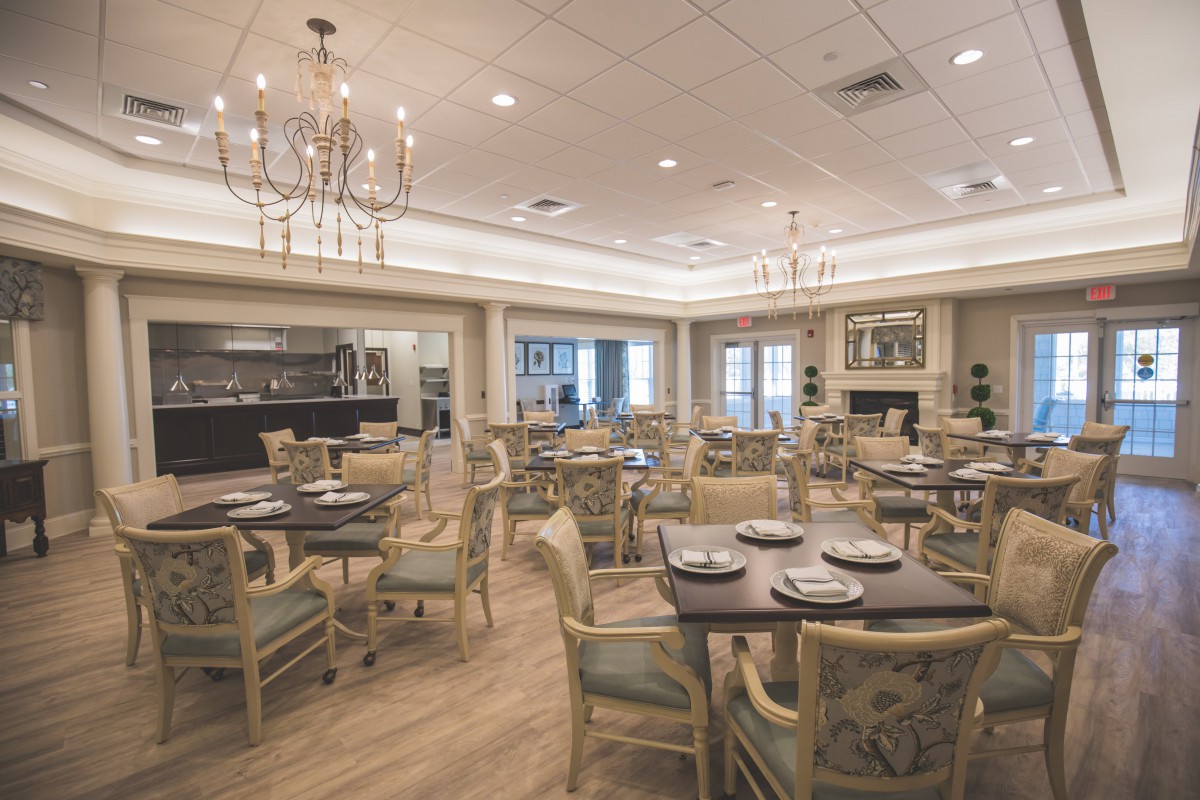 An elegant dining room with neatly set tables and chandeliers.