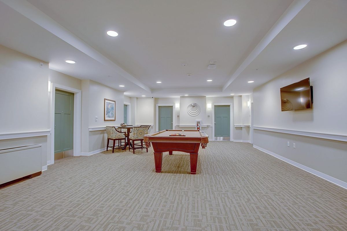 A spacious game room featuring a pool table, seating area, and modern lighting.