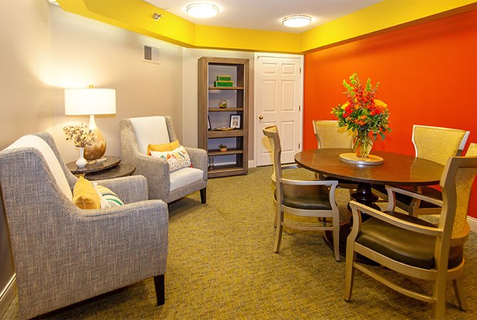 A cozy living room with vibrant decor featuring a round table, armchairs, and colorful walls.