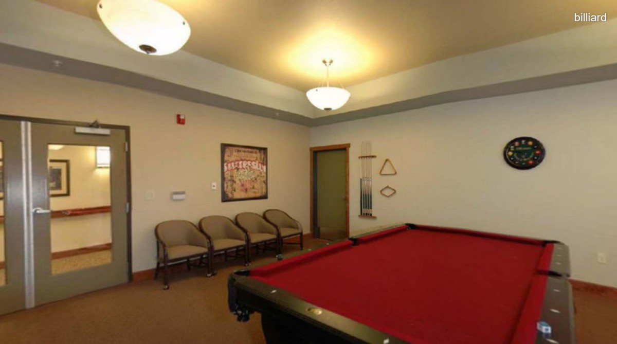 A cozy billiard room featuring a red pool table and seating area.